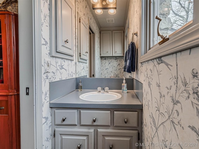 bathroom with visible vents, vanity, and wallpapered walls