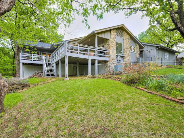 back of property featuring fence, a wooden deck, stairs, and a yard