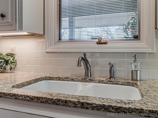 interior details featuring light stone counters, decorative backsplash, and sink