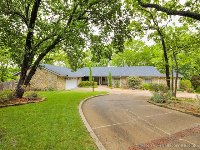 ranch-style home with fence, an attached garage, driveway, stone siding, and a front yard