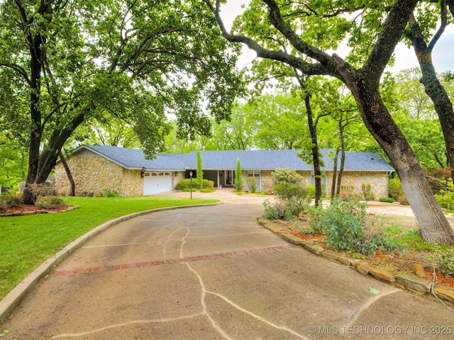 single story home with a garage, stone siding, a front yard, and concrete driveway