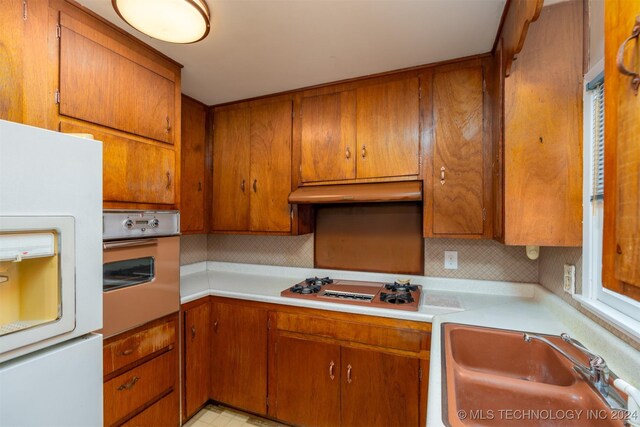 606 N B Ave, Cleveland, OK 74020 - kitchen featuring freestanding refrigerator, oven, a sink, under cabinet range hood, and light countertops