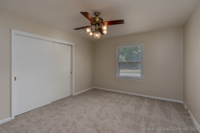 unfurnished bedroom featuring a closet, light colored carpet, and ceiling fan