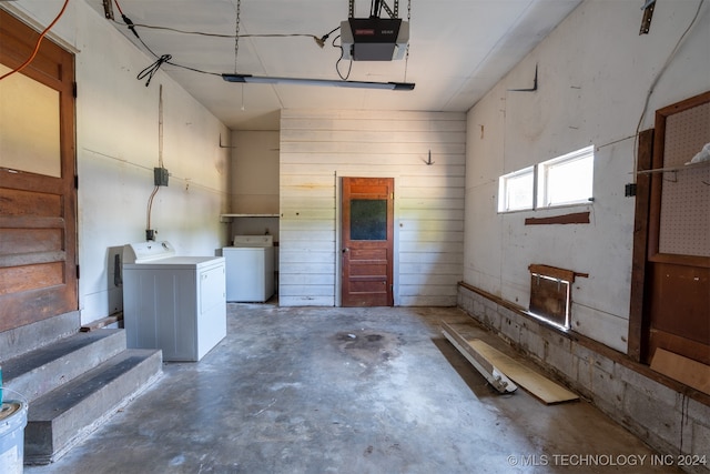 garage featuring a garage door opener, wood walls, and washing machine and dryer