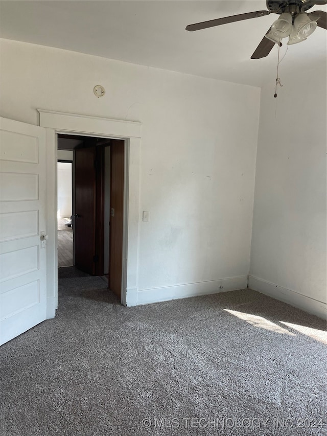 spare room featuring dark colored carpet and ceiling fan