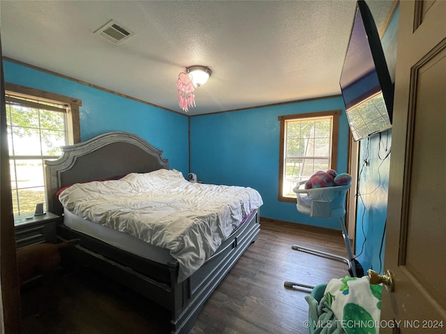 bedroom with dark wood-type flooring, visible vents, and a textured ceiling