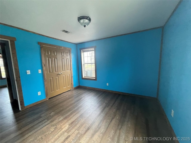 unfurnished bedroom featuring baseboards, a closet, visible vents, and wood finished floors