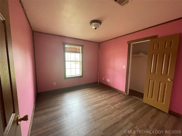 unfurnished bedroom featuring a closet, dark wood-style flooring, visible vents, and baseboards