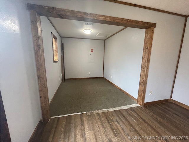 empty room featuring dark wood-type flooring, visible vents, and baseboards