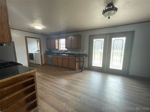 kitchen with stainless steel appliances, dark wood-type flooring, a sink, french doors, and dark countertops