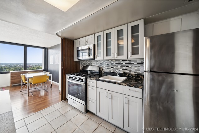 kitchen with stainless steel appliances, sink, white cabinetry, and light hardwood / wood-style floors