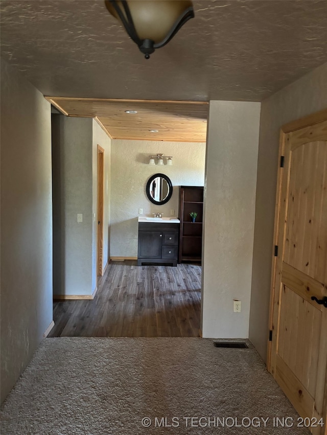 hallway with a textured ceiling, sink, and dark hardwood / wood-style floors