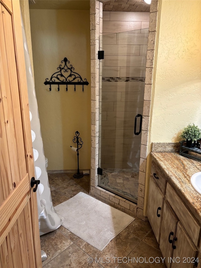 bathroom with a shower with door, vanity, toilet, and tile patterned flooring