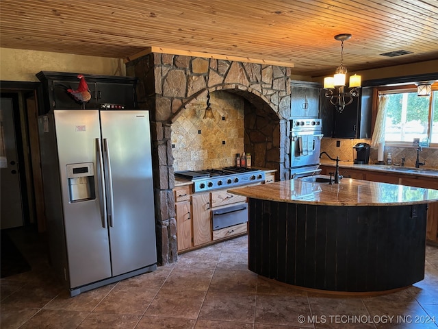 kitchen with an island with sink, stainless steel appliances, sink, and light stone counters