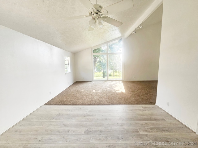 carpeted empty room with vaulted ceiling, a textured ceiling, and ceiling fan