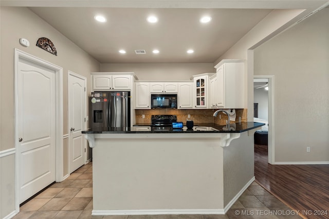 kitchen featuring black appliances, backsplash, kitchen peninsula, white cabinetry, and light wood-type flooring