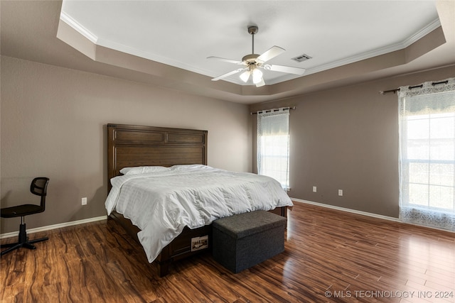 bedroom featuring dark hardwood / wood-style flooring, ceiling fan, a raised ceiling, and crown molding