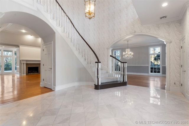 foyer with ornamental molding, a wealth of natural light, and a notable chandelier