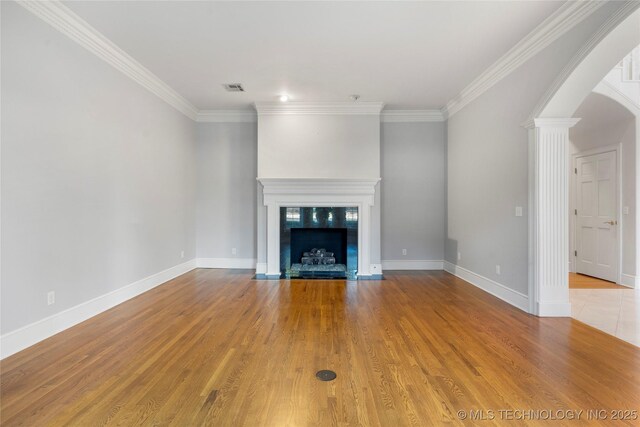 unfurnished living room featuring a high end fireplace, ornamental molding, decorative columns, and light wood-type flooring