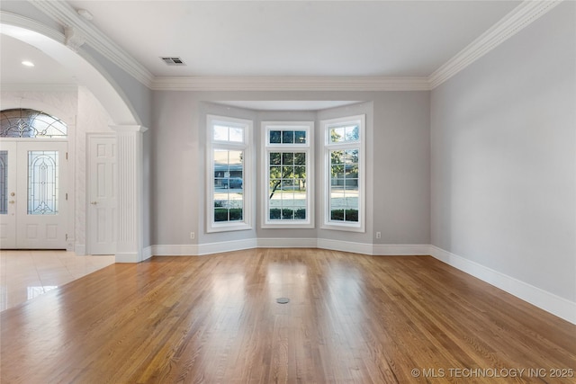 foyer entrance with ornamental molding, light wood-type flooring, and plenty of natural light