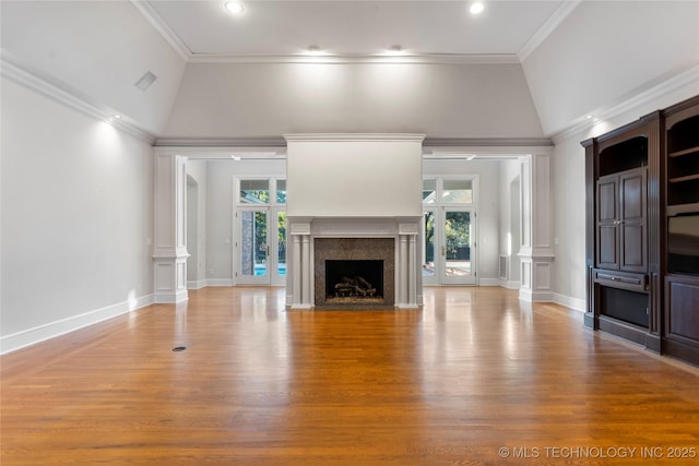 unfurnished living room featuring crown molding, a wealth of natural light, decorative columns, and a premium fireplace