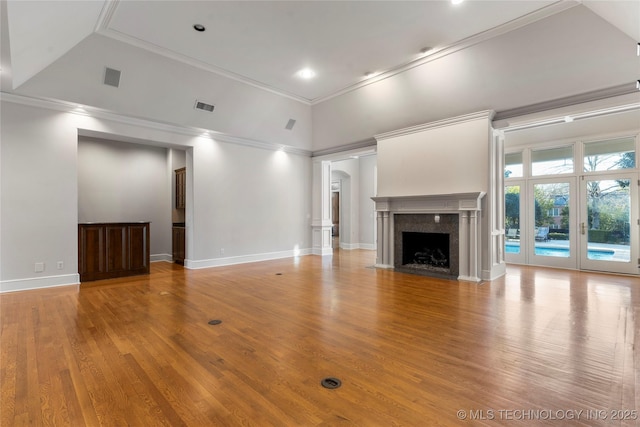 unfurnished living room with hardwood / wood-style flooring, a high end fireplace, ornamental molding, and high vaulted ceiling