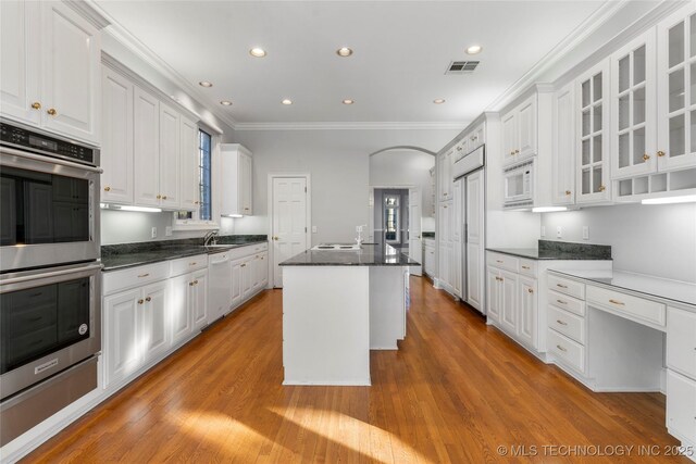 kitchen featuring white appliances, a center island, white cabinets, and light wood-type flooring