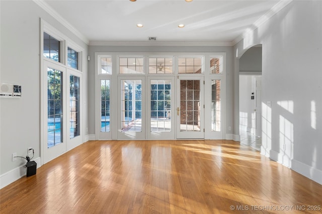 unfurnished room with ornamental molding and light wood-type flooring