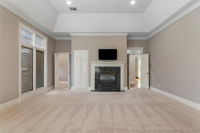 unfurnished living room with a high end fireplace, a tray ceiling, and light carpet