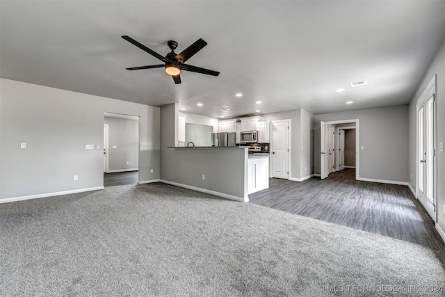 unfurnished living room with ceiling fan and dark carpet