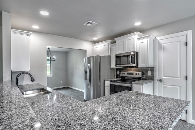 kitchen with white cabinets, appliances with stainless steel finishes, dark stone countertops, and sink