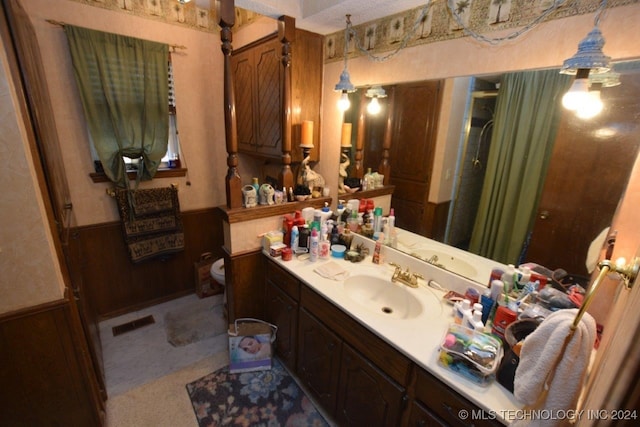 bathroom with vanity, toilet, and wooden walls