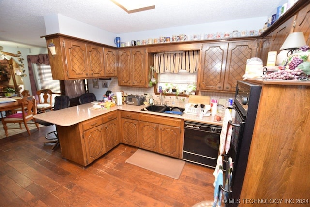 kitchen with dishwasher, dark hardwood / wood-style flooring, kitchen peninsula, and a textured ceiling