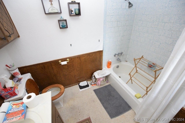 full bathroom featuring vanity, toilet, wood walls, and shower / tub combo with curtain