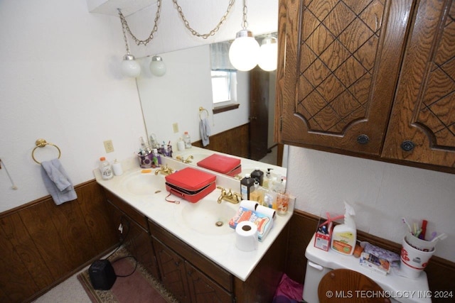 bathroom with vanity, toilet, and wooden walls