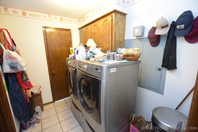 laundry area featuring light tile patterned floors, cabinets, and washing machine and dryer