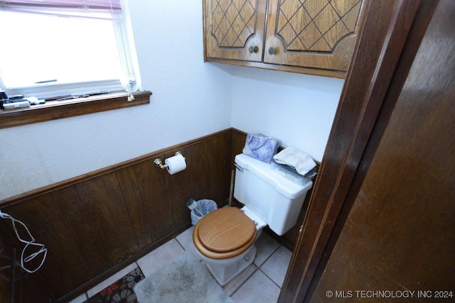 bathroom with wood walls, tile patterned flooring, and toilet