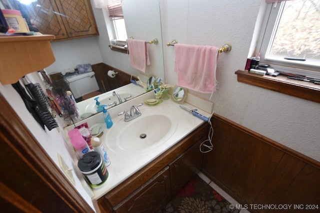 bathroom with vanity, toilet, and wooden walls