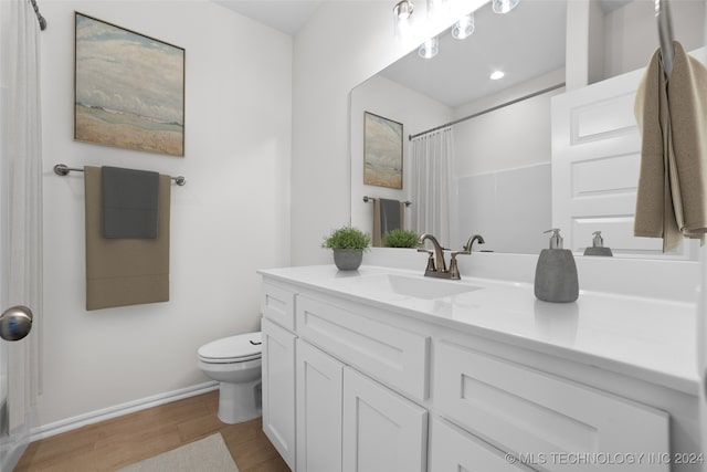 bathroom with curtained shower, hardwood / wood-style floors, toilet, and vanity