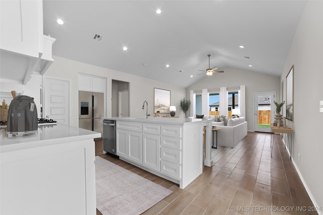 kitchen with light wood-type flooring, white cabinetry, lofted ceiling, an island with sink, and ceiling fan