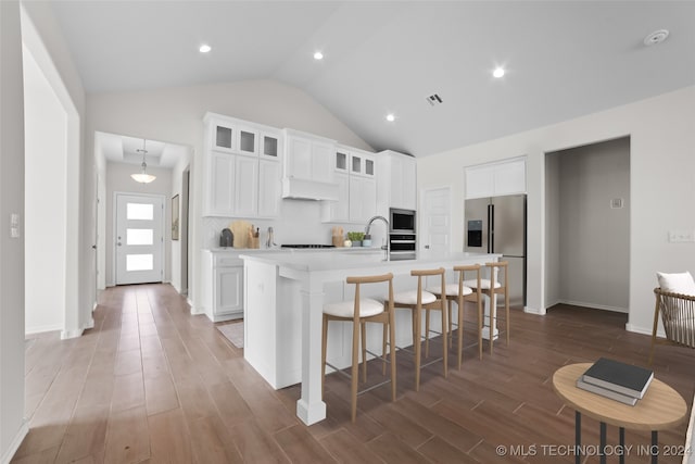 kitchen with a kitchen island with sink, appliances with stainless steel finishes, hardwood / wood-style flooring, and white cabinets