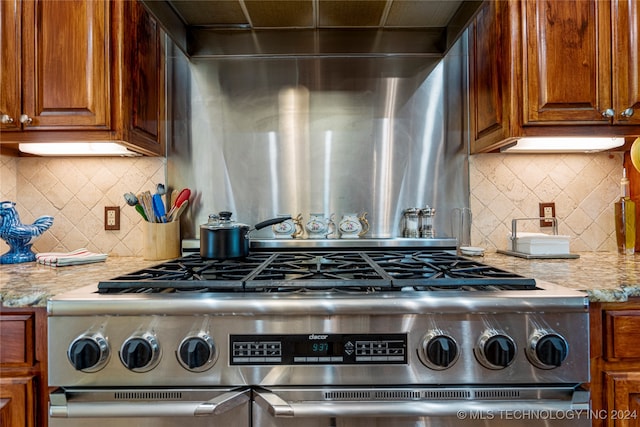 kitchen with high end stainless steel range oven, backsplash, and light stone counters