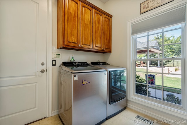 laundry area with light tile patterned floors, washing machine and clothes dryer, and cabinets