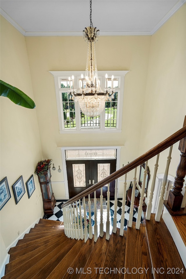 staircase featuring wood-type flooring, a wealth of natural light, a chandelier, and crown molding