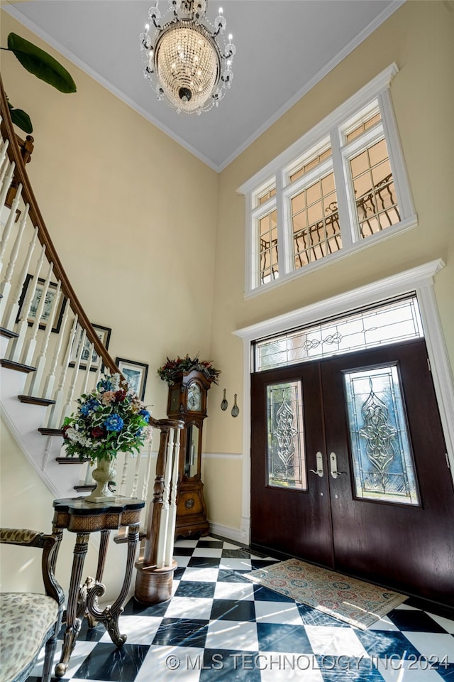 entryway with ornamental molding, french doors, a wealth of natural light, and an inviting chandelier