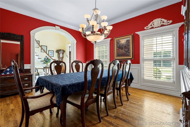 dining area featuring ornamental molding, wood-type flooring, and an inviting chandelier