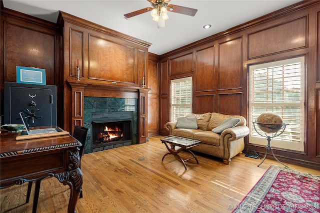 living room with a tiled fireplace, ceiling fan, and light hardwood / wood-style floors