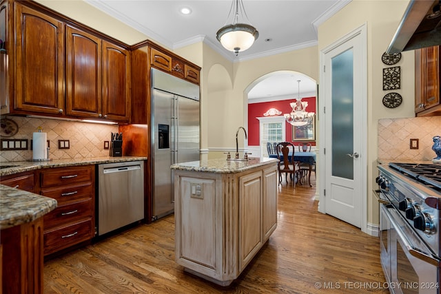 kitchen with an island with sink, crown molding, dark hardwood / wood-style flooring, and premium appliances