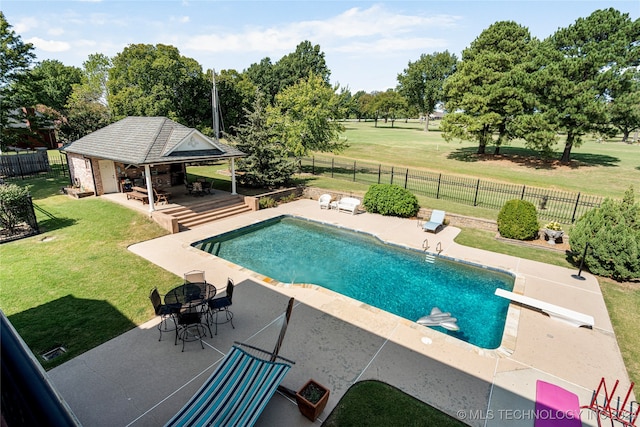 view of swimming pool featuring a diving board, a lawn, and a patio area