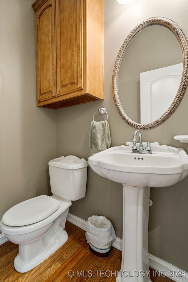 bathroom with toilet, wood-type flooring, and sink